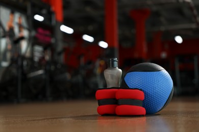 Photo of Medicine ball, bottle and weighting agents on floor in gym. Space for text