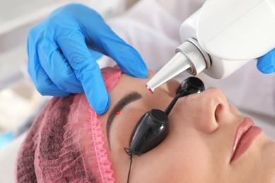 Woman undergoing laser tattoo removal procedure in salon, closeup