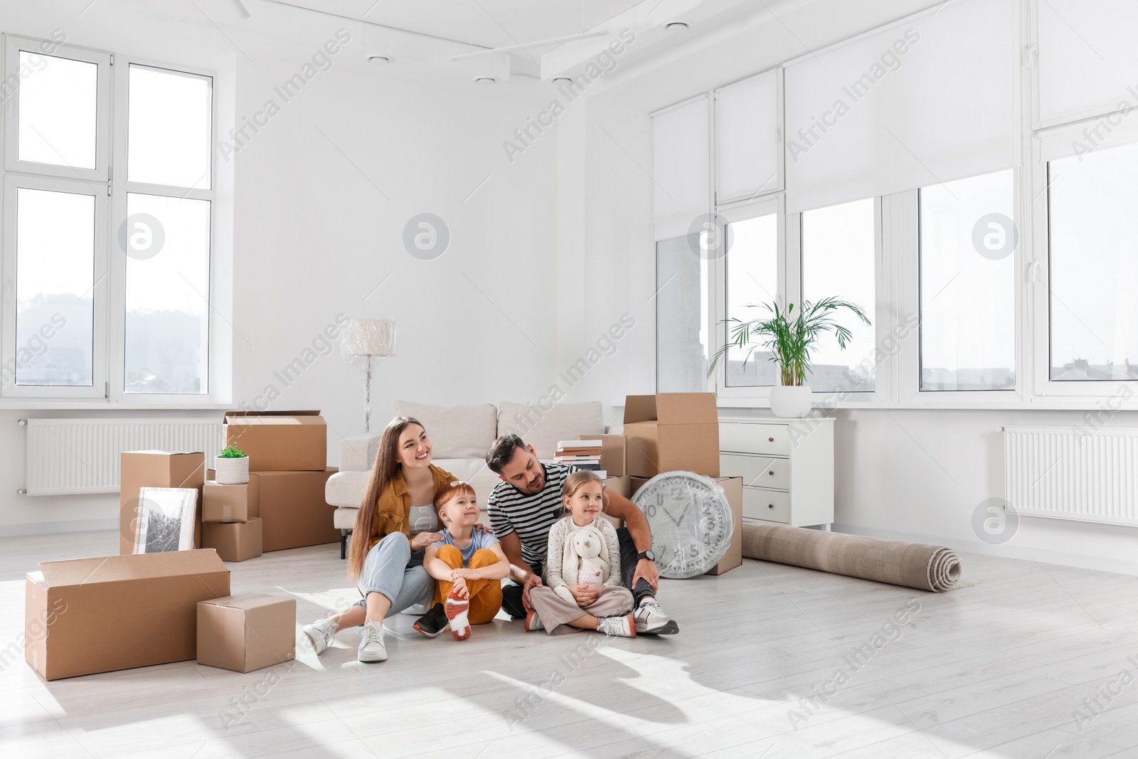 Photo of Happy family sitting on floor in new apartment. Moving day