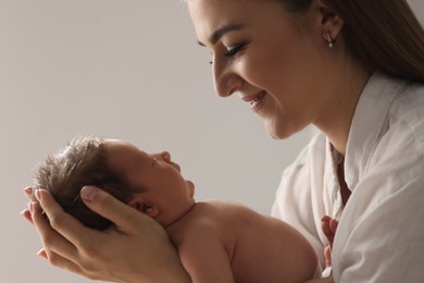 Photo of Mother holding her newborn baby on light grey background
