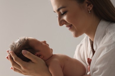 Mother holding her newborn baby on light grey background