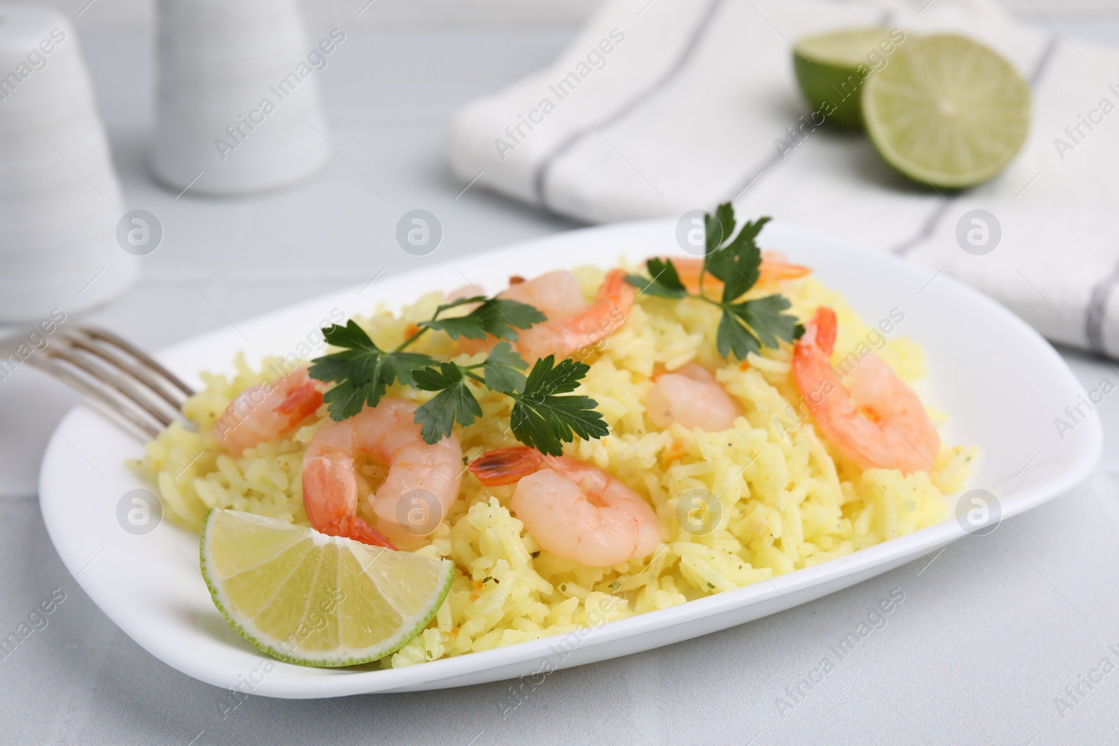 Photo of Delicious risotto with shrimps, lime and parsley on white table, closeup