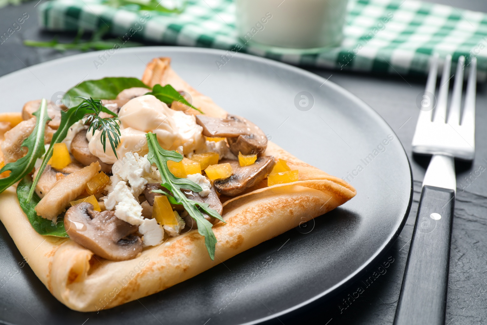 Photo of Delicious breakfast with thin pancakes on black table, closeup