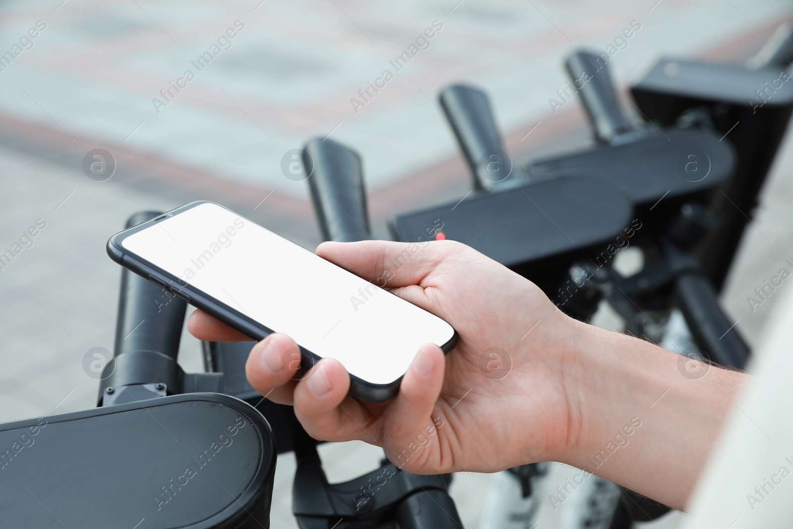 Photo of Man using smartphone to pay and unblock electric kick scooter outdoors, closeup