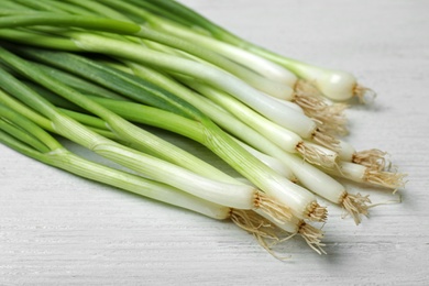 Photo of Bunch of fresh green onions on white wooden background, closeup