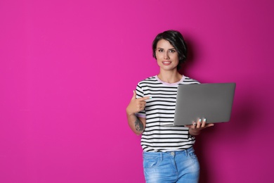 Young woman with modern laptop on color background