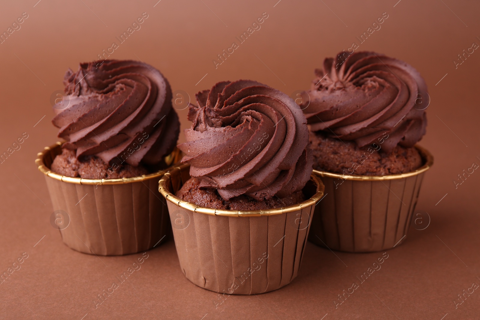 Photo of Delicious chocolate cupcakes on brown background, closeup