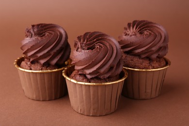 Photo of Delicious chocolate cupcakes on brown background, closeup