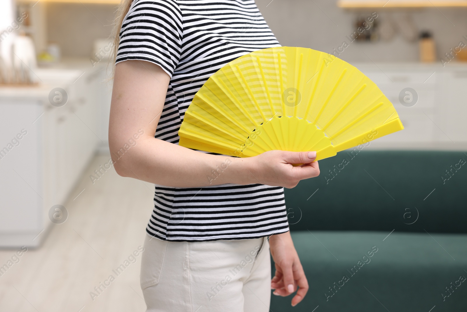 Photo of Woman with yellow hand fan at home, closeup
