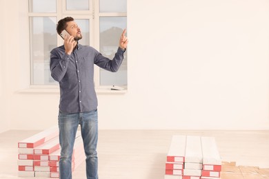 Photo of Man talking on phone in apartment during repair, space for text