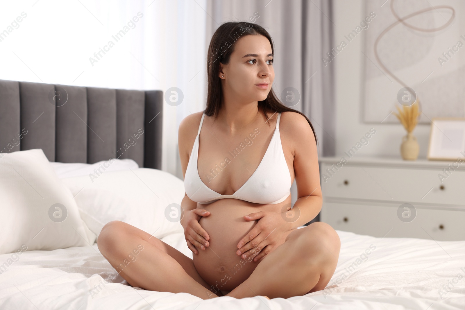 Photo of Beautiful pregnant woman in stylish comfortable underwear on bed at home