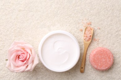 Photo of Flat lay composition with moisturizing cream in open jar and other body care products on light textured table