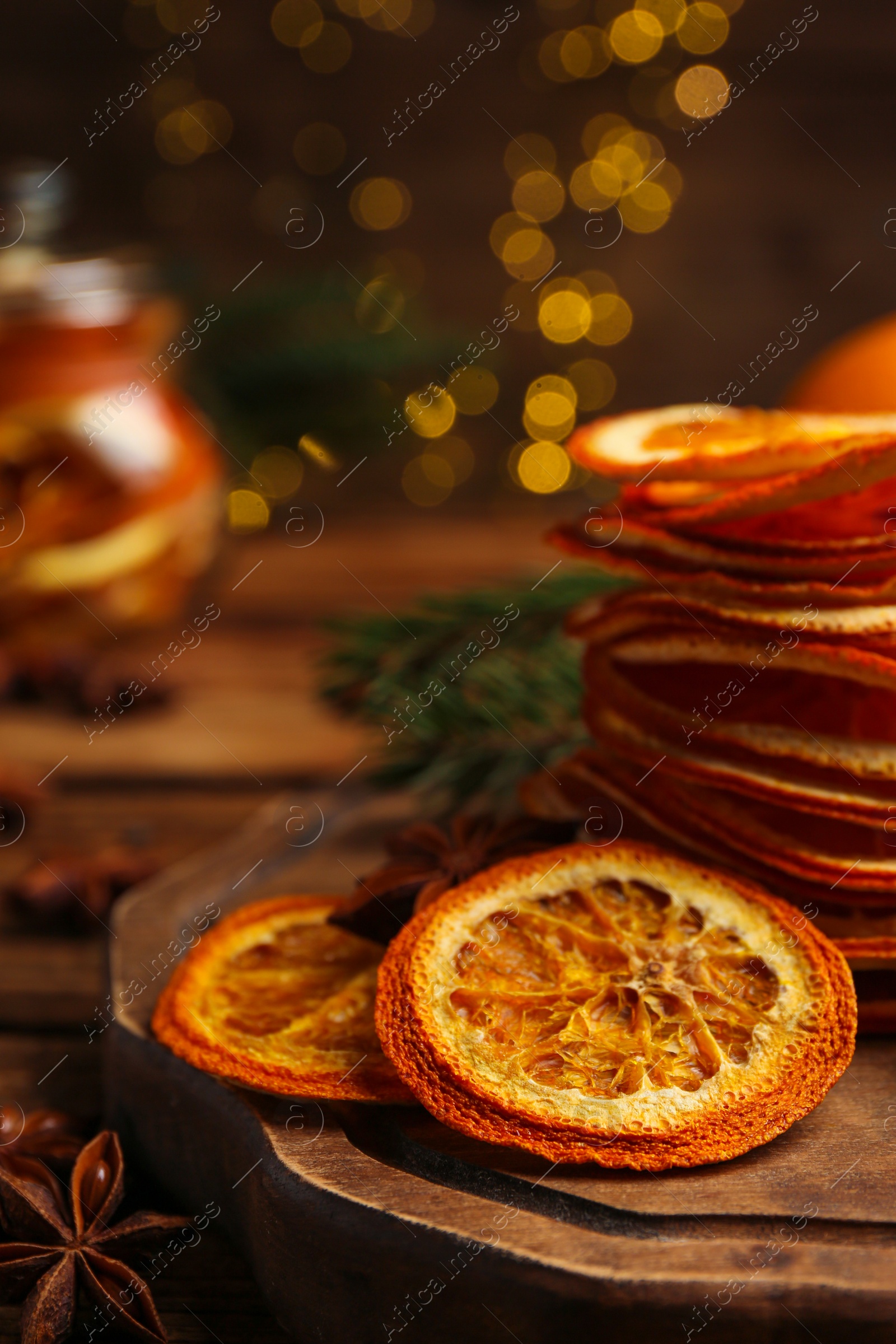 Photo of Dry orange slices and anise stars on wooden table, closeup. Bokeh effect