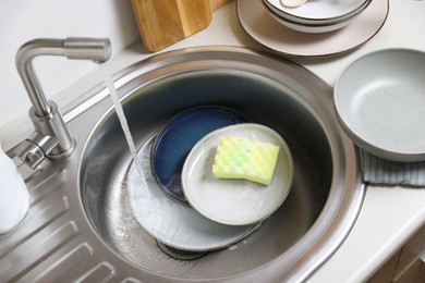 Washing plates and sponge in kitchen sink