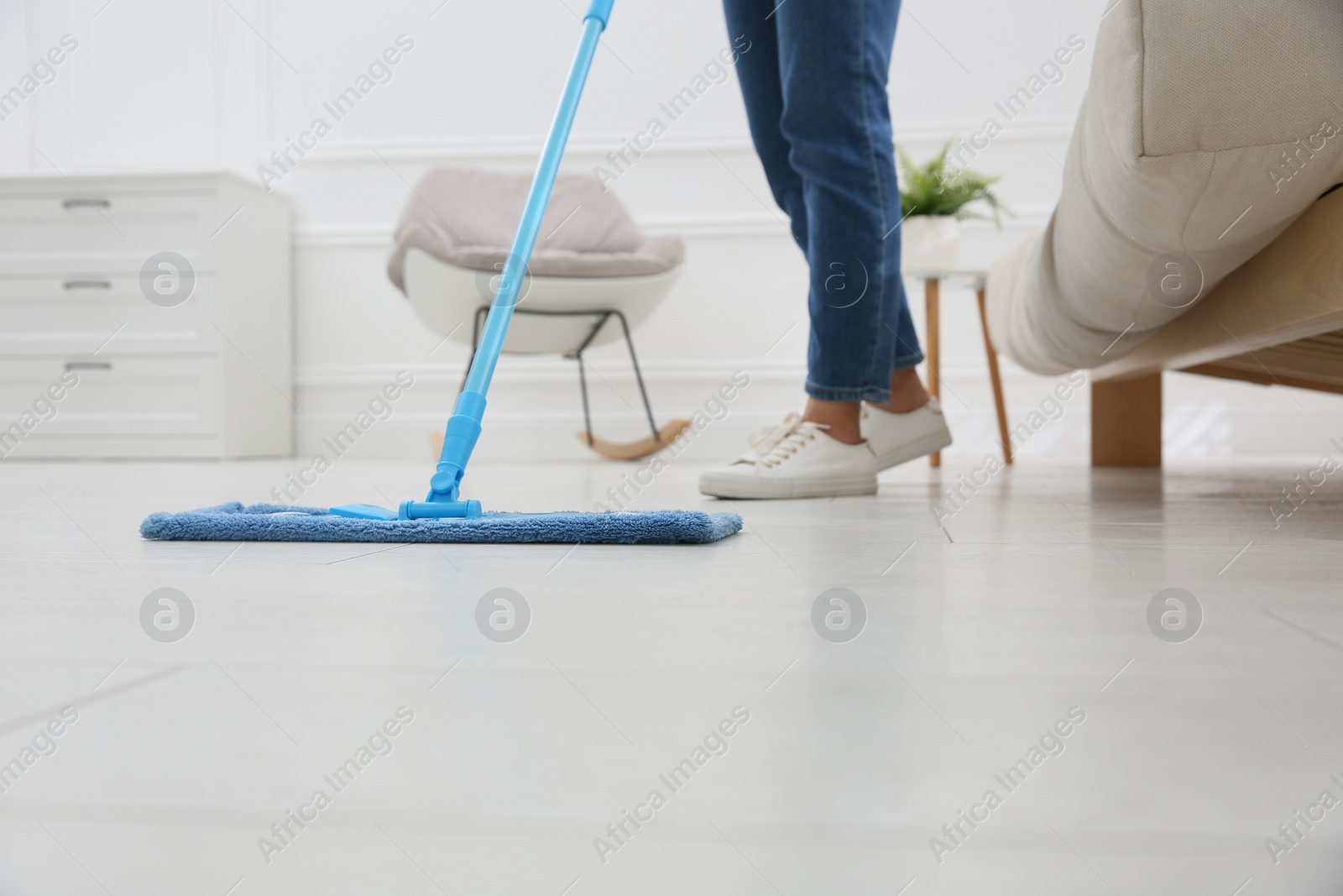 Photo of Woman cleaning parquet floor with mop at home, closeup