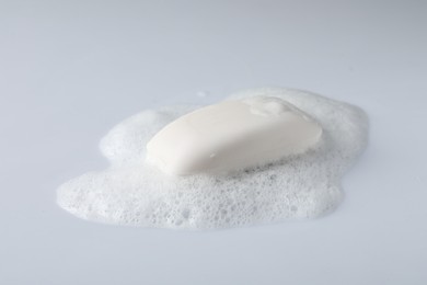 Soap with fluffy foam on white background