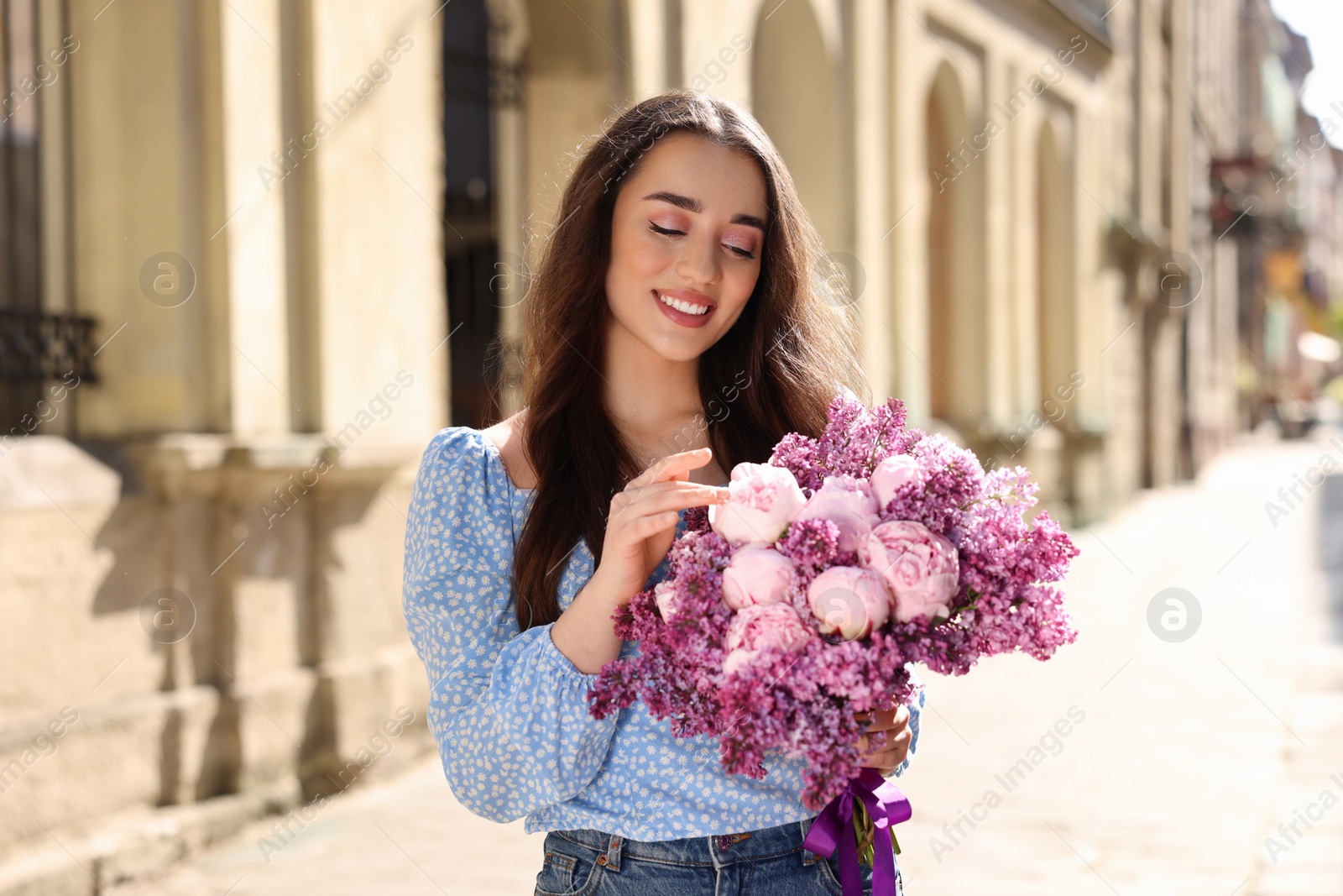 Photo of Beautiful woman with bouquet of spring flowers on city street