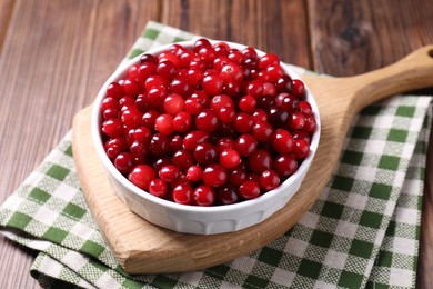 Fresh ripe cranberries in bowl on wooden table, closeup