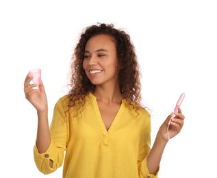 Young African American woman with menstrual cup and tampon on white background