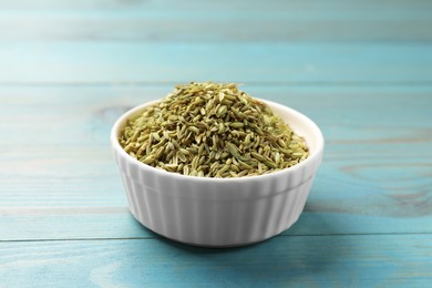 Photo of Fennel seeds in bowl on light blue wooden table, closeup