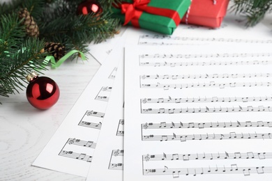 Photo of Composition with Christmas music sheets with notes on white wooden background, closeup