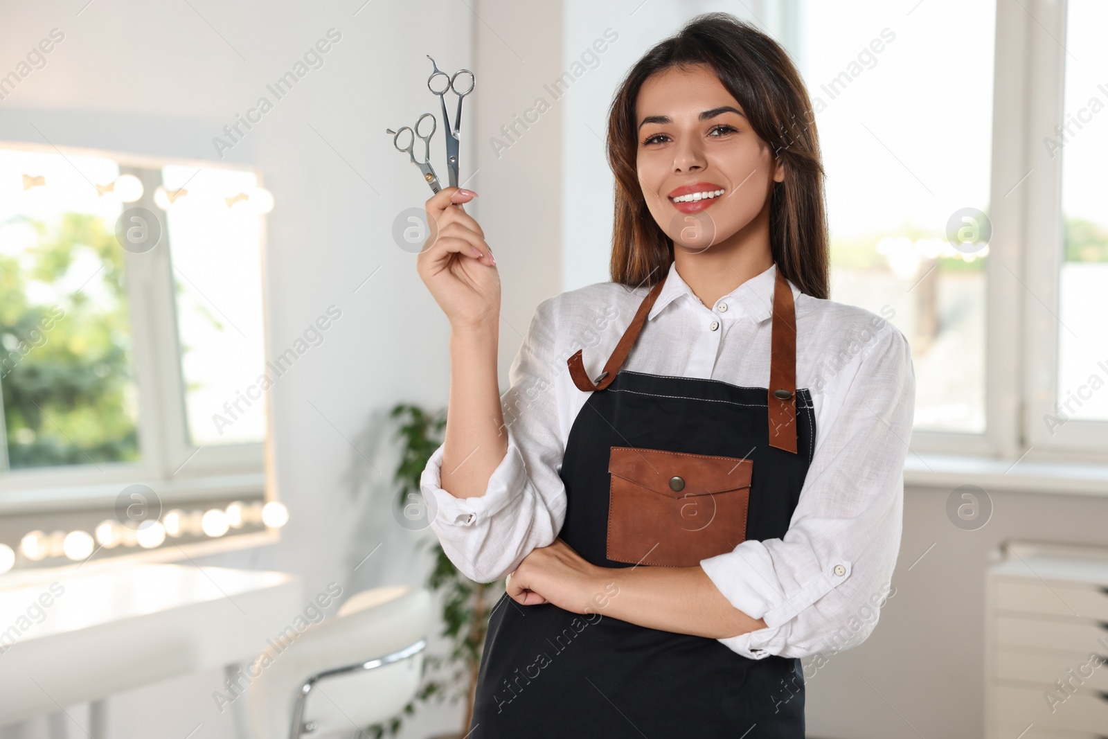 Photo of Portrait of happy hairdresser with professional scissors in beauty salon. Space for text