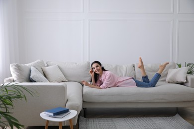 Woman with headphones resting on sofa in living room
