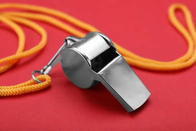 Photo of One metal whistle with cord on red background, closeup