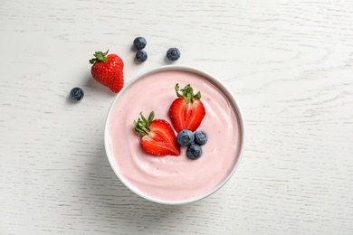 Photo of Bowl with yogurt and berries on wooden background, top view