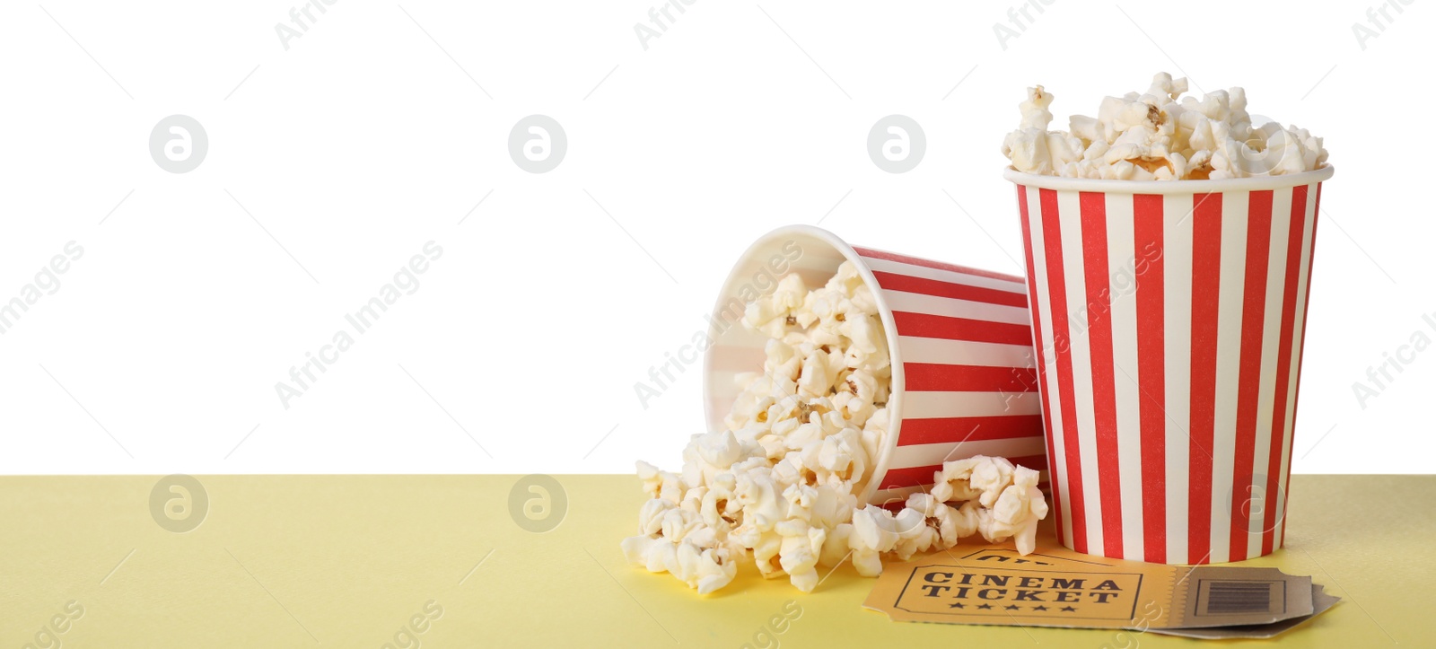 Photo of Cups with delicious popcorn and tickets on table against white background