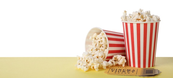 Photo of Cups with delicious popcorn and tickets on table against white background