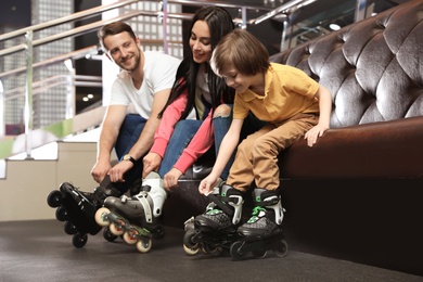 Photo of Happy family putting on roller skates indoors