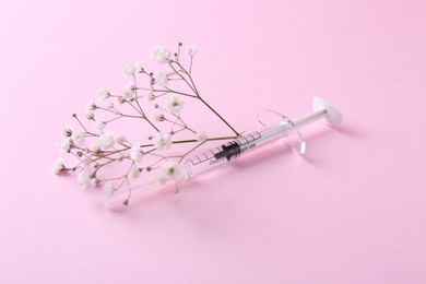 Cosmetology. Medical syringe and gypsophila on pink background