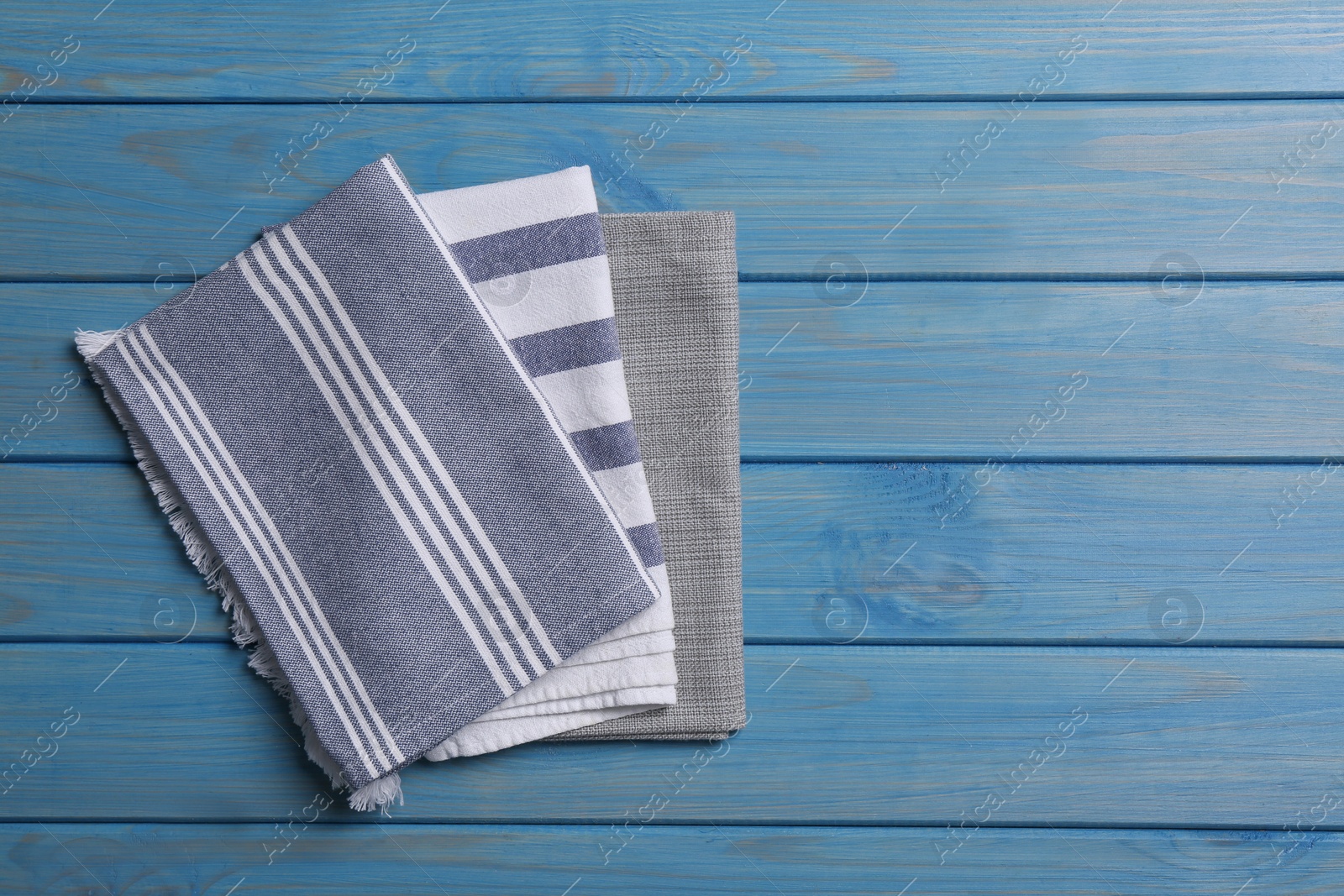 Photo of Different kitchen towels on blue wooden table, top view. Space for text