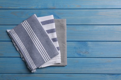 Photo of Different kitchen towels on blue wooden table, top view. Space for text