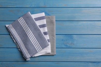 Different kitchen towels on blue wooden table, top view. Space for text