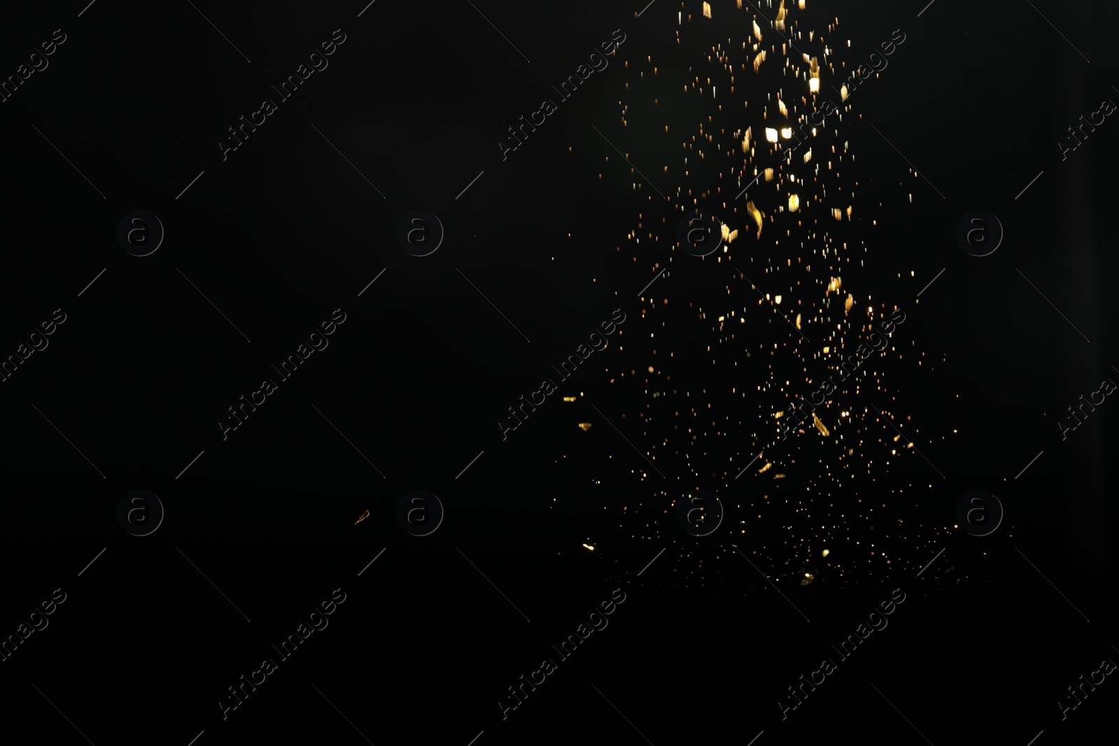 Photo of Shiny golden glitter falling down on black background. Bokeh effect