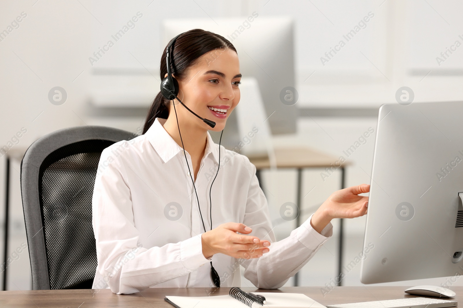 Photo of Hotline operator with headset working on computer in office