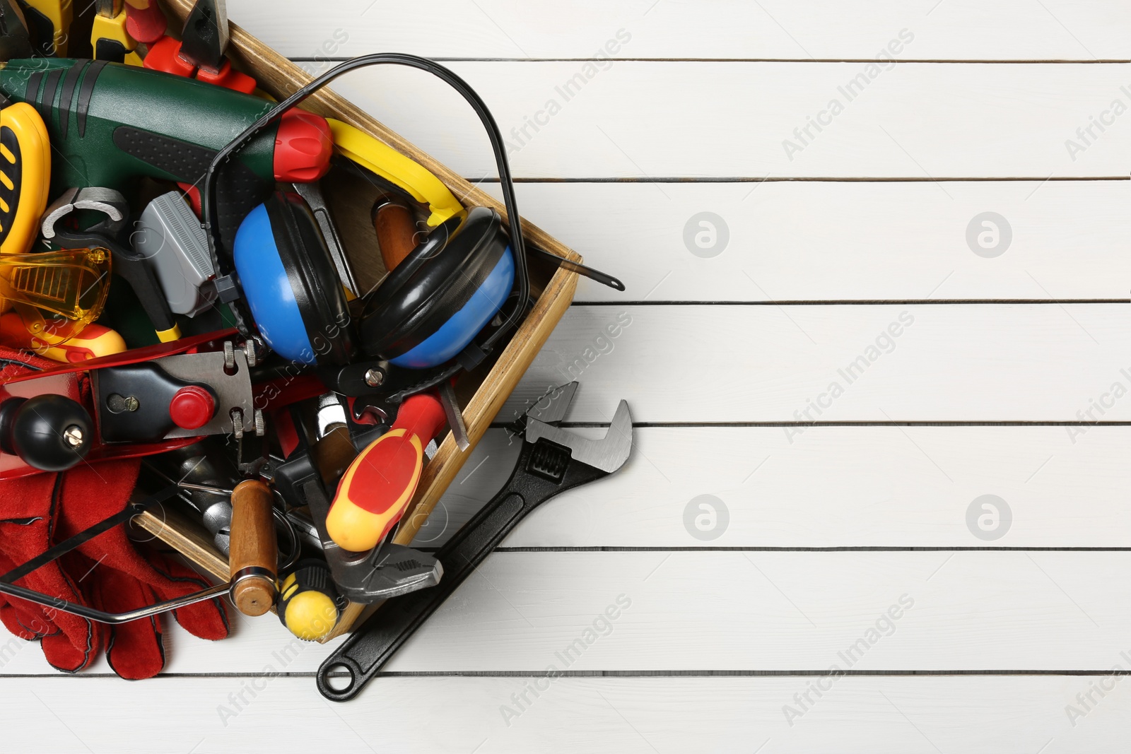 Photo of Box with professional tools for repair and wrench on white wooden table, flat lay. Space for text