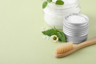 Photo of Toothbrush, dental products and herbs on light olive background, closeup. Space for text