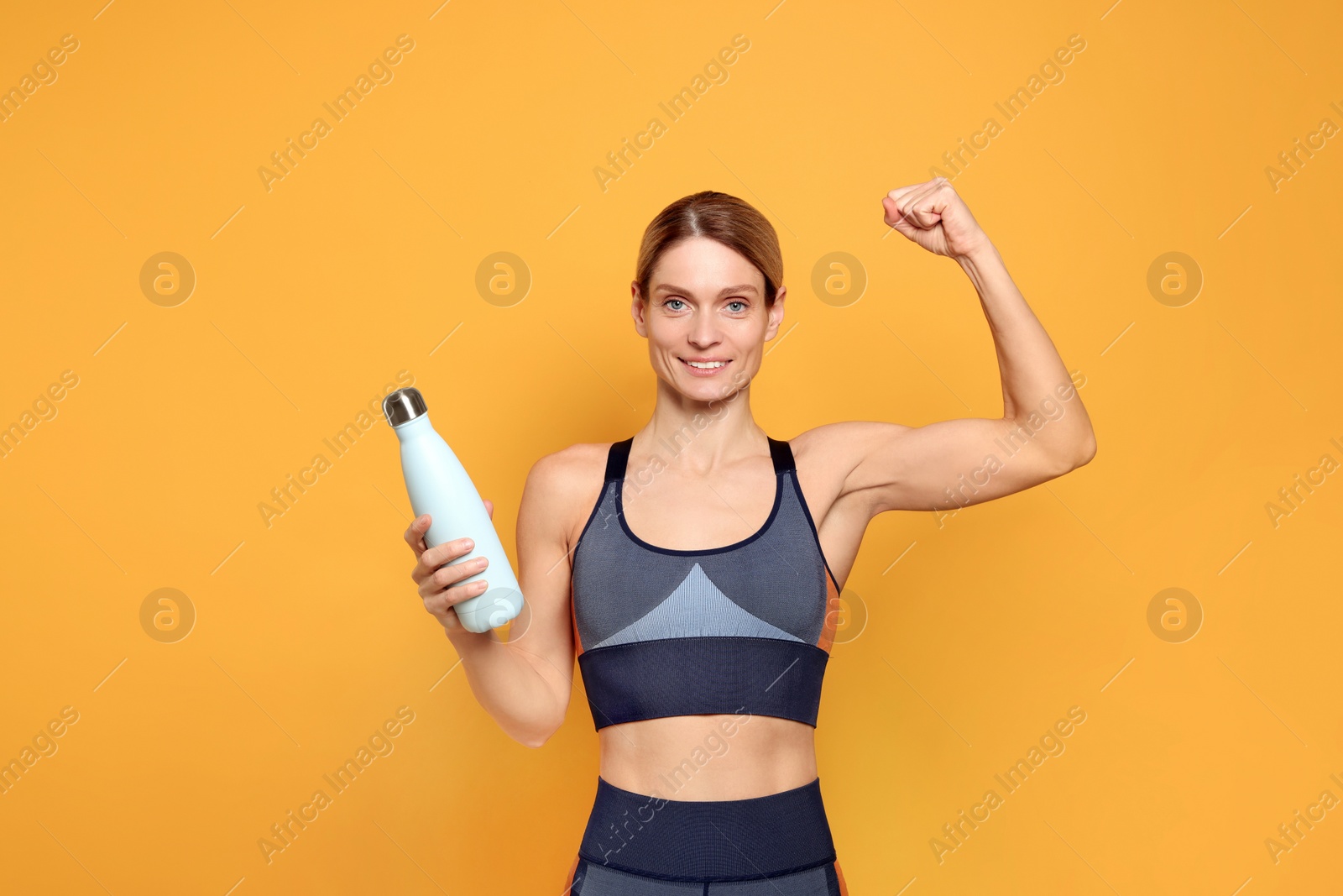Photo of Sportswoman with thermo bottle on yellow background