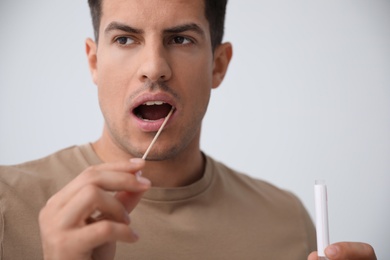 Man taking sample for DNA test on light background