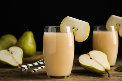 Photo of Fresh pear juice in glass and fruits on wooden table, closeup