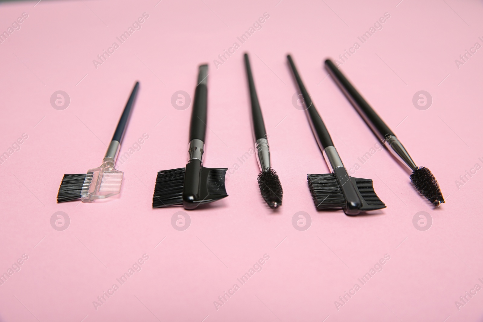 Photo of Set of professional makeup brushes on pink background