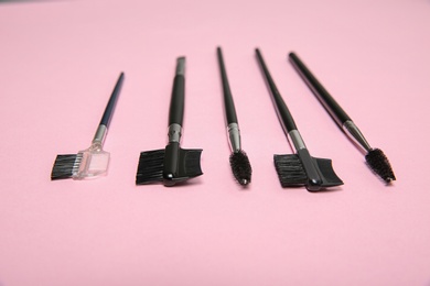 Set of professional makeup brushes on pink background