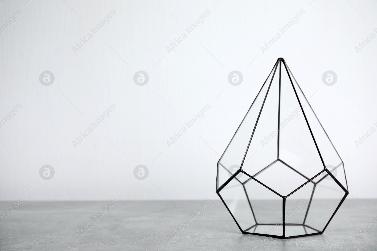 Photo of Empty glass florarium vase on grey table, space for text