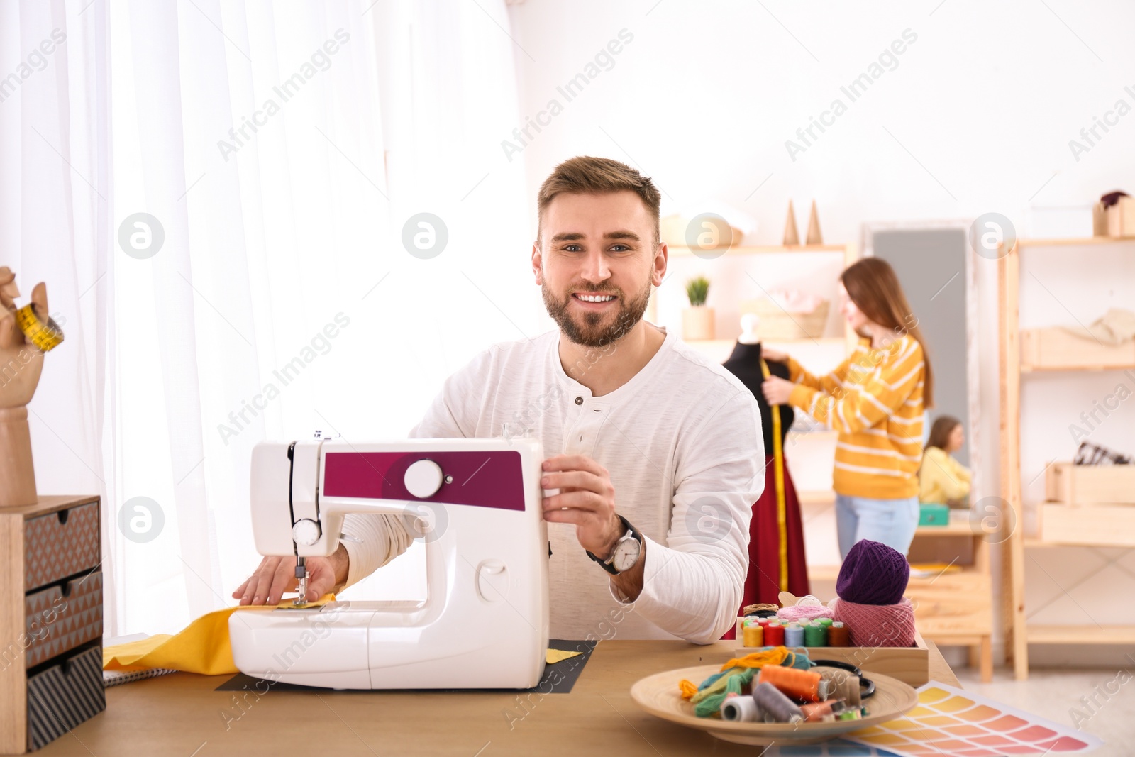 Photo of Fashion designer sewing new clothes with machine in studio