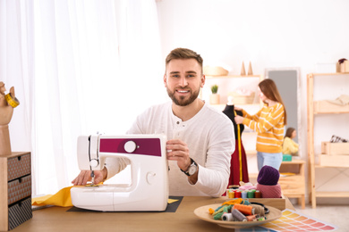 Fashion designer sewing new clothes with machine in studio