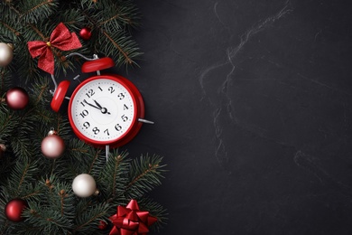 Flat lay composition with alarm clock and Christmas decor on black slate background, space for text. New Year countdown