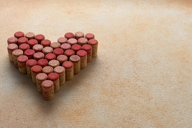 Photo of Heart made of wine bottle corks on textured table. Space for text